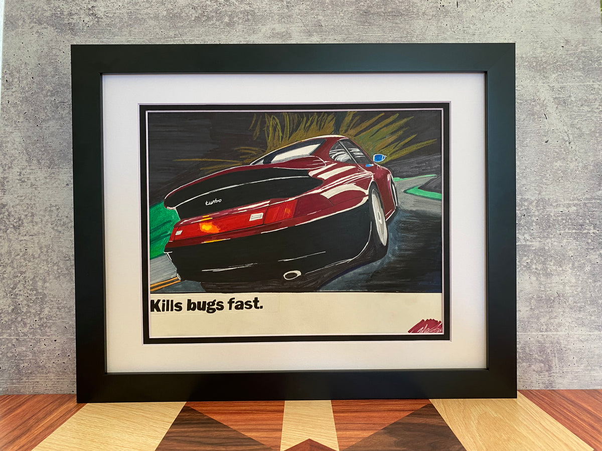 Angled view of framed Porsche Kills Bugs Fast poster recreation on a wood surface